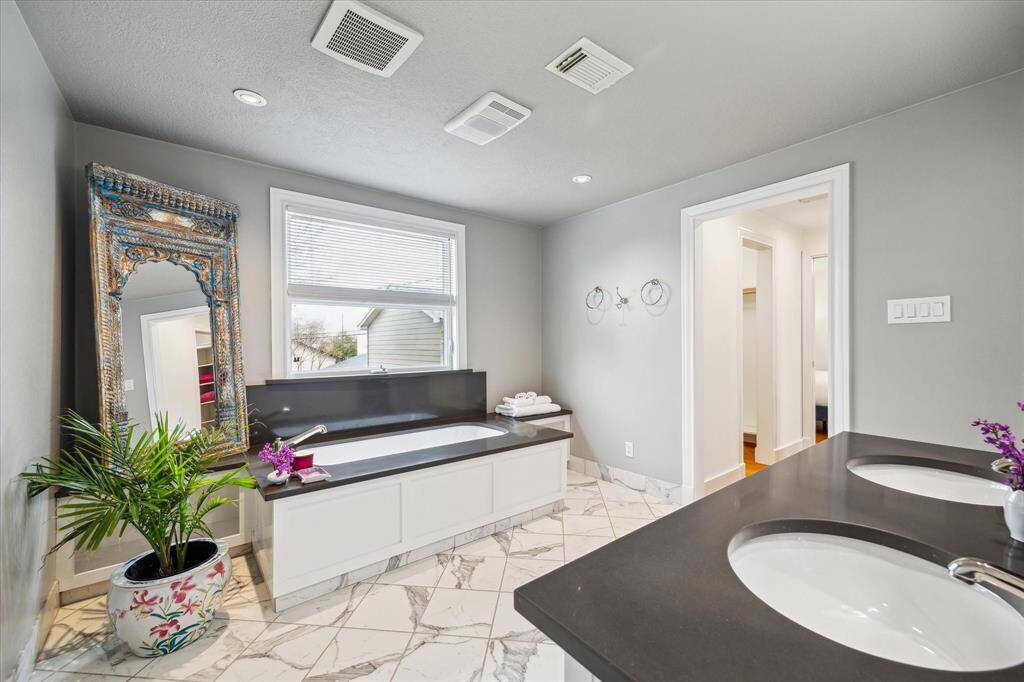 The Primary Bath retreat is separated from the Primary Bedroom by a hallway with two walk-in closets.