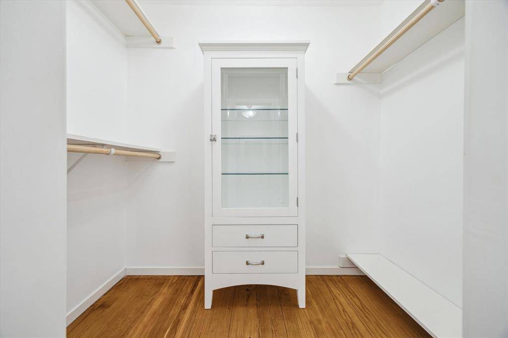 Walk in closet 1 with glass front RH cabinet with drawers and shelves, space for hanging long apparel, shelving for shoes.