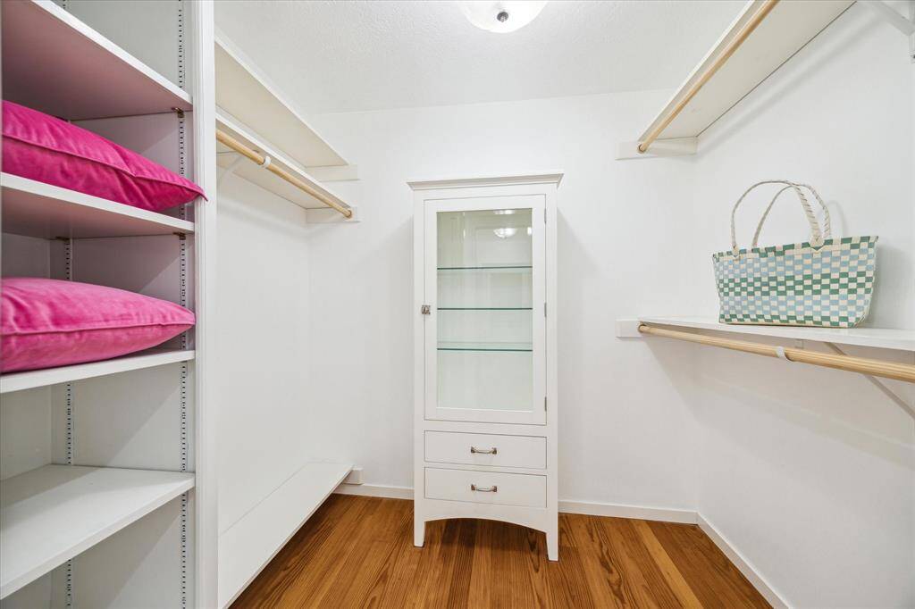 Walk in closet 2 with glass front RH cabinet with drawers and shelves, space for hanging long apparel, shelving for shoes.