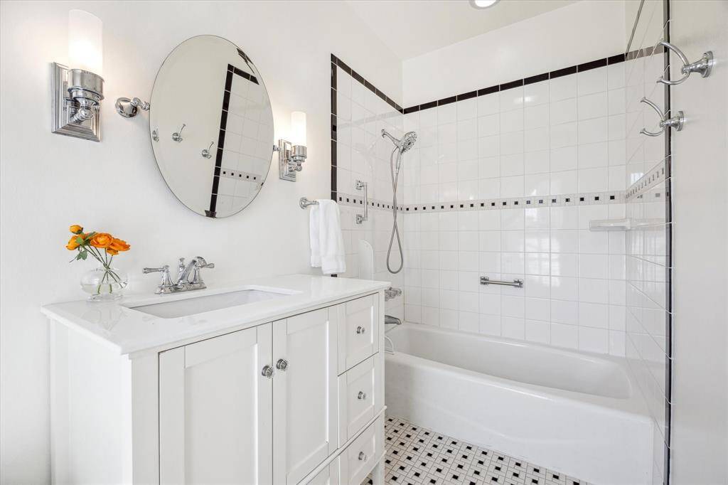 Secondary bath 1 is updated with a shower/bath combo, vanity with storage and decorative tilework.