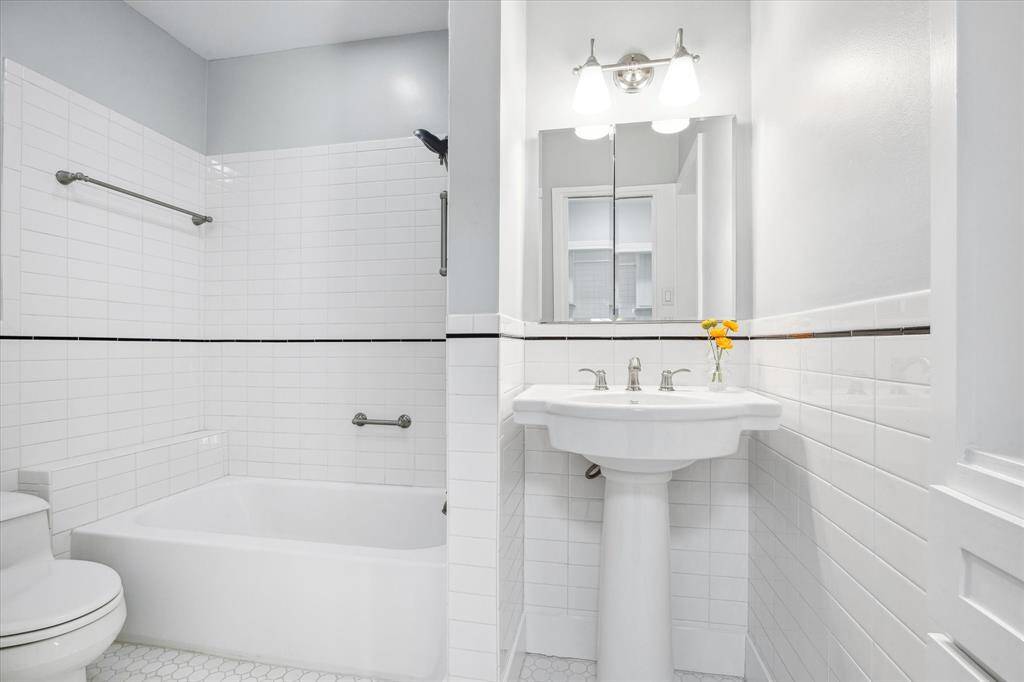 Secondary bath 2 updated with pedestal sink, tub/shower combo, and storage.