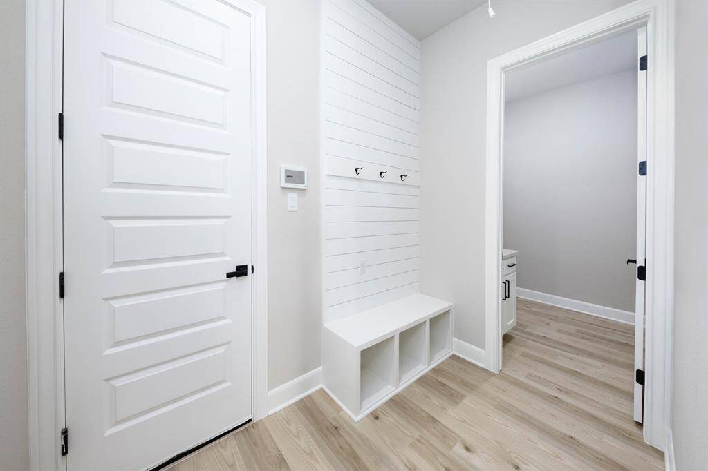 Step into organization and style with this bright, functional mudroom featuring built-in cubbies for storage, sleek black hooks for coats and bags, and a modern shiplap accent wall. Conveniently located off the garage entry and leading to the in home utility room, it offers a seamless transition from outdoors to indoors—perfect for busy households!