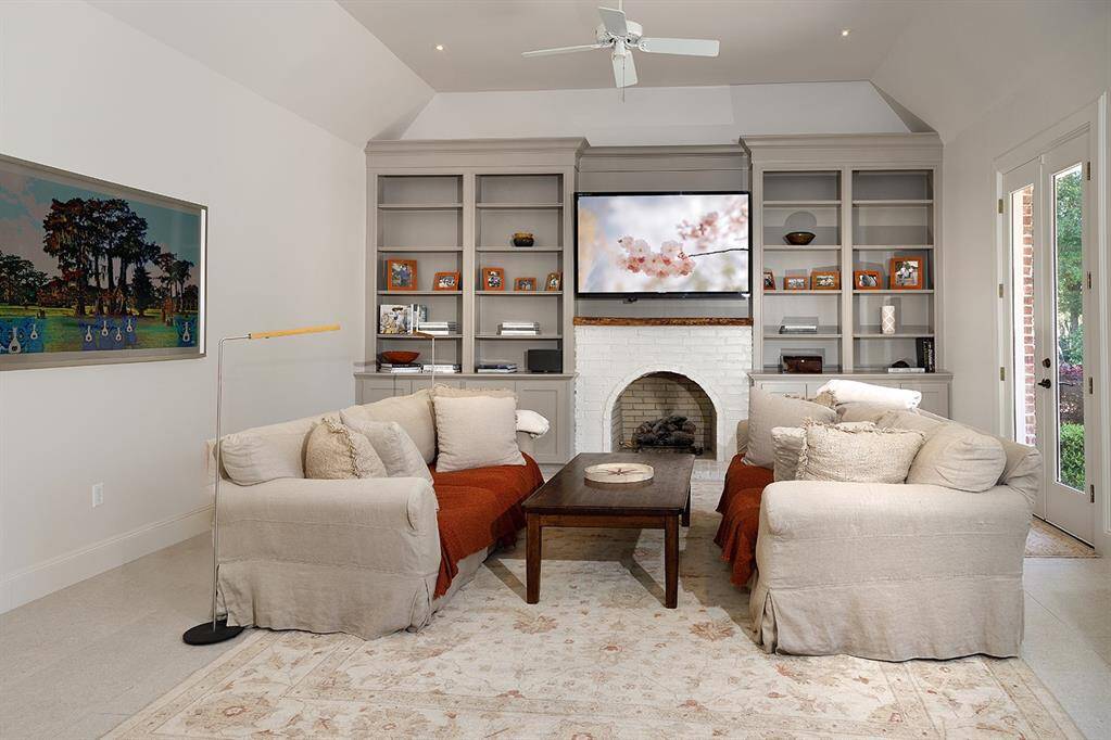 This family room off the kitchen has a wood burning fireplace and doors that lead to the patio and pool.