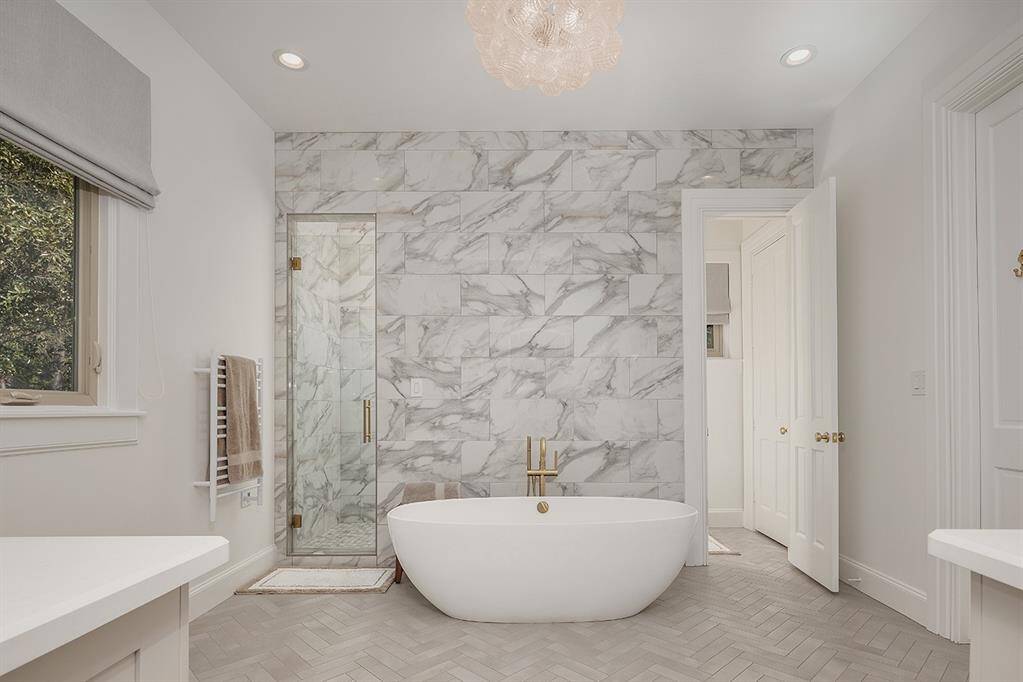 Victoria & Albert soaking tub, dual sinks with soft close cabinetry and herringbone tile floors in this gorgeous primary bath. The huge walk in closet has a center island for storage and is great when packing for a trip!