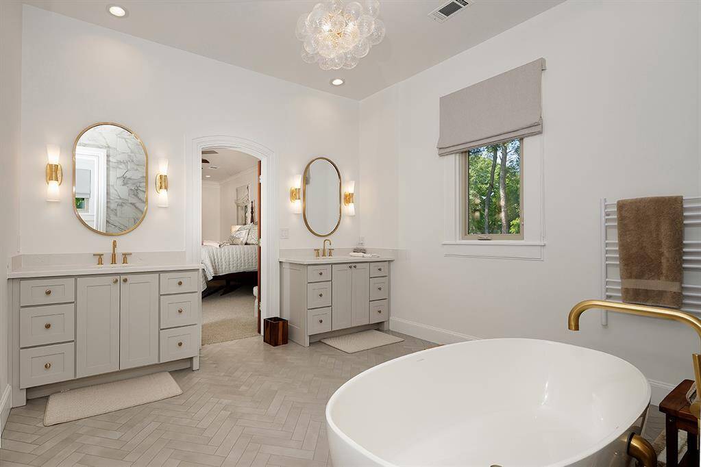 This remodeled primary bath also features new window treatments, a towel warmer, new mirrors and designer light fixtures.