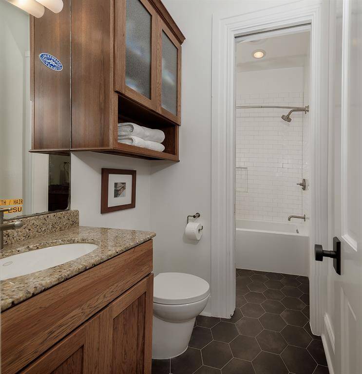Remodeled bath with new cabinetry, honey comb tile flooring, new tub and shower tile surround.
