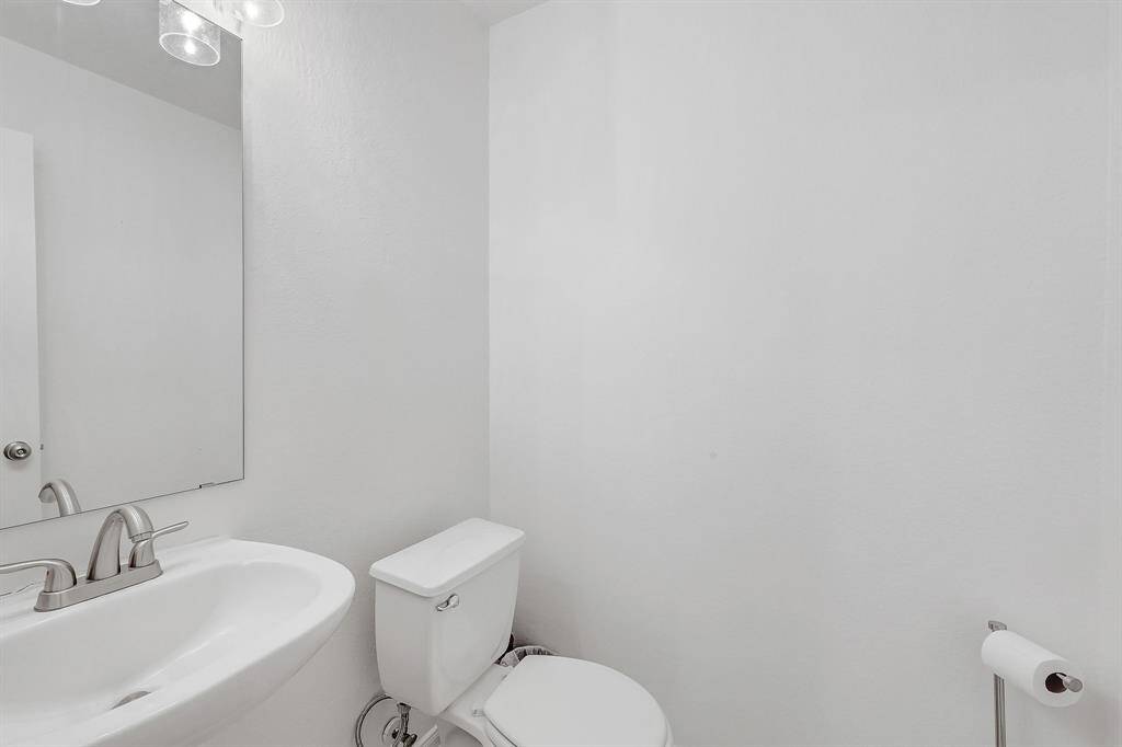 The half bath on the first floor is in between the living areas. It features the bright paint color of the rest of the home and recently updated  light fixtures.