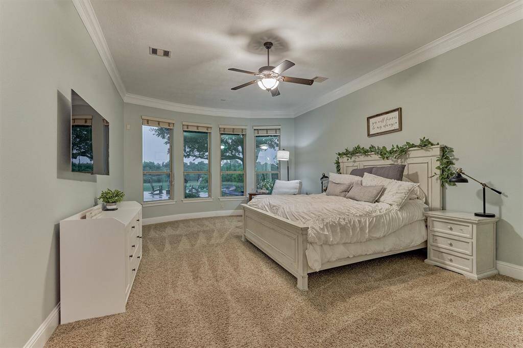 Primary bedroom with crown molding and offering amazing views of the backyard.