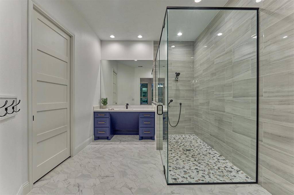 Huge bathroom with large shower and beautiful blue bathroom cabinet and sink.