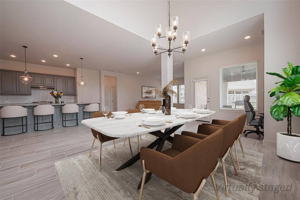Gather in this beautiful 2-story ceiling-height dining area with it's stunning 9-light chandelier, expansive windows flooding the space with natural light and a convenient workstation just steps away, perfect for homework, office work, or planning meals.