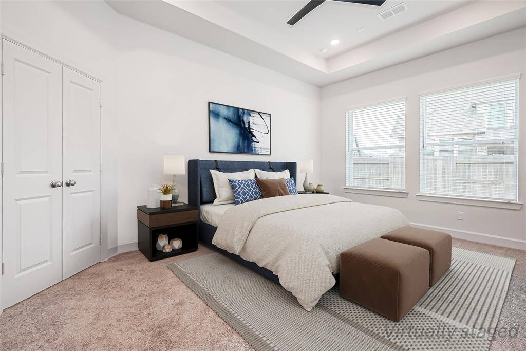 Escape to tranquility in this stunning primary bedroom, a serene retreat featuring plush carpets, tray ceiling, recessed lights, oversized windows, and a calming ambiance.