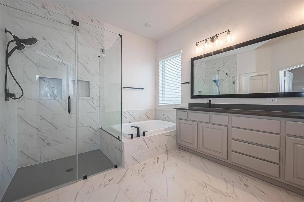 Indulge in the ultimate spa experience in this breathtaking primary bathroom featuring sleek surfaces, oversized soaking tub, frameless shower with C-Pull handle and double niches, oversized mirror and modern lighting. Rejuvenation and relaxation awaits.