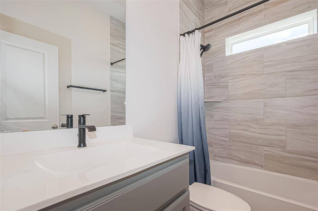 The secondary bathroom boasts tiled shower surround up to the ceiling, corner shelf, and a fixed window to welcome more natural light.