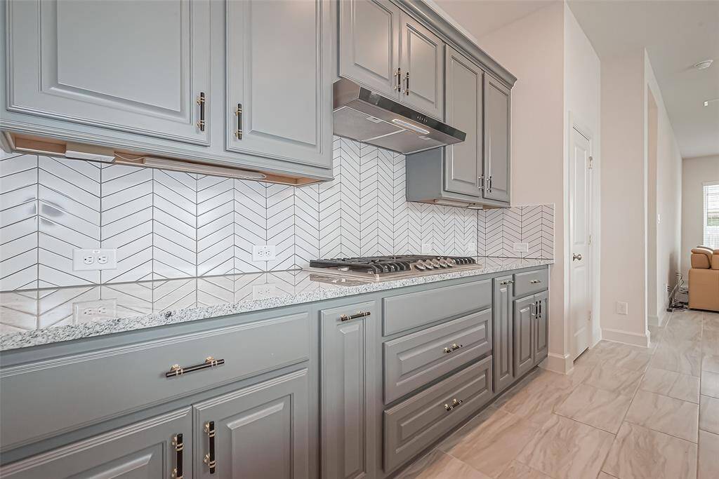 Enjoy ample countertop space, a 5-burner gas stove with vent, and another view of the chevron tile backsplash.