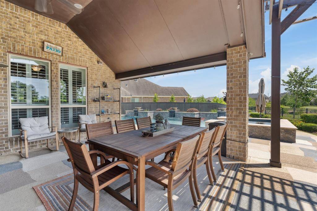 Gather with family and friends under the covered patio, complete with a spacious dining area and views of the pool and greenbelt beyond.