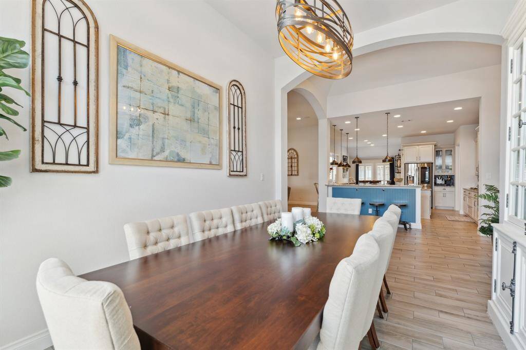 The formal dining room features a wall of windows that flood the space with natural light and a sleek modern chandelier. It offers the perfect balance—open to the living areas yet distinctly defined for elegant dining.