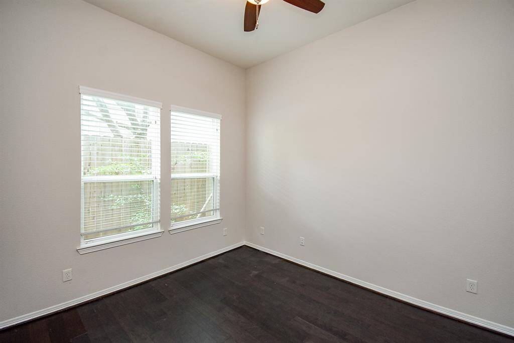 Nestled on the first floor, this bright bedroom pairs large windows with rich hardwood flooring and a ceiling fan—perfectly balancing comfort and calm.