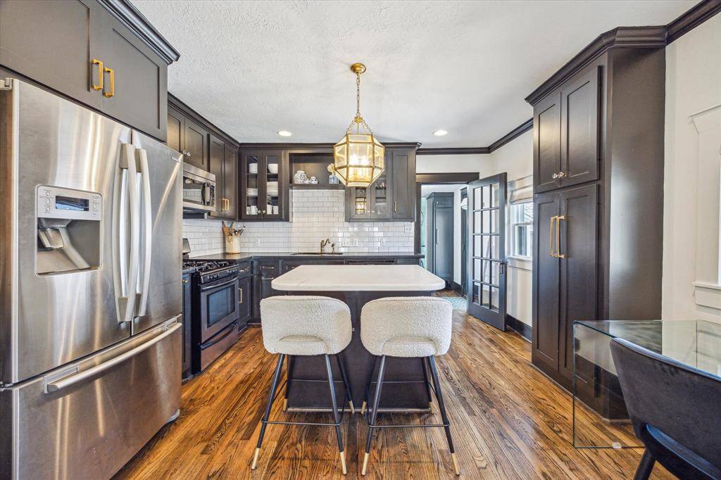 Designer kitchen with ceiling-height cabinets & island with seating for 2