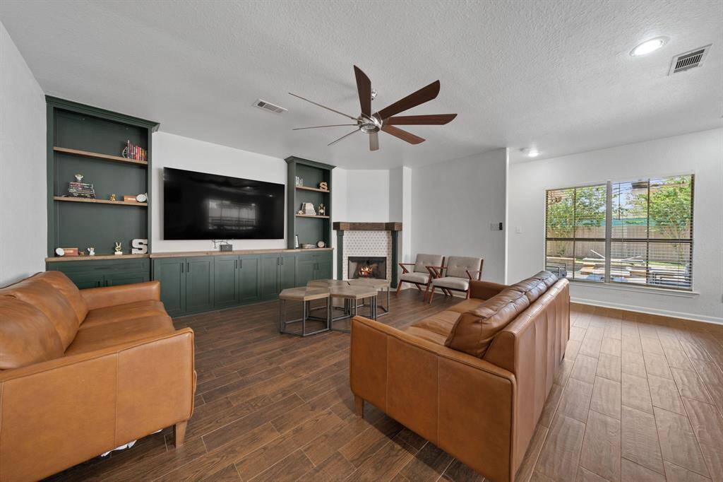 This stunning living room boasts wood tile flooring, a dark stained ceiling fan, recessed lighting, fireplace to keep you warm this winter, and a large window providing a beautiful view of the backyard and tons of natural light in throughout the day.