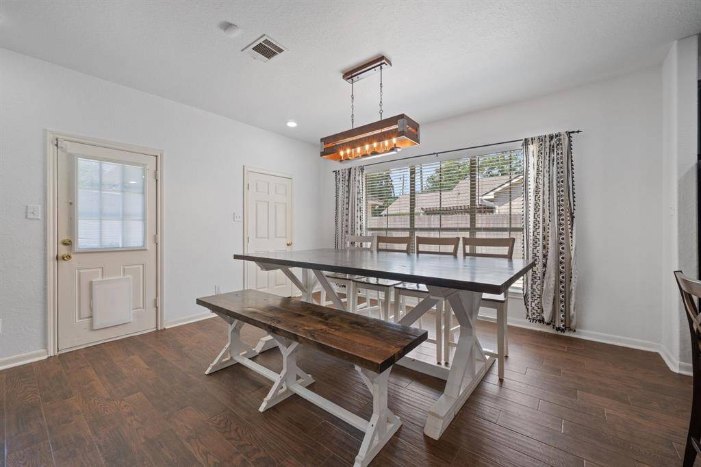 This dining area boasts a gorgeous chandelier, wood tile floors, recessed lighting, and a large window with incredible views to the backyard.