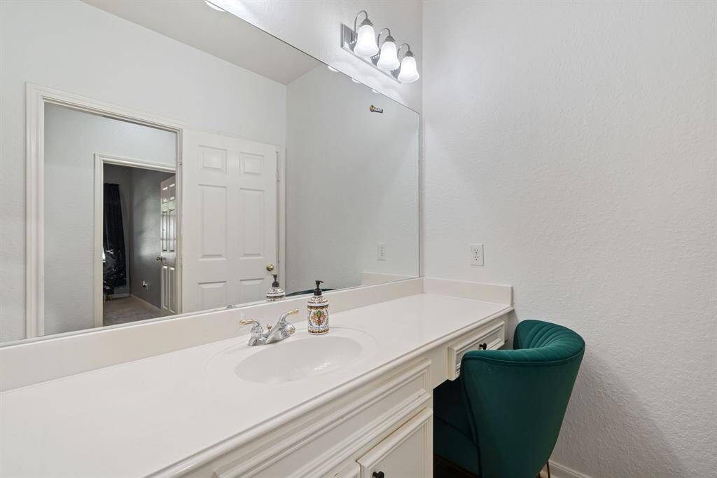 Beautiful secondary bathroom featuring white cabinetry, granite countertops, a vanity area, large mirror, and vanity lights.
