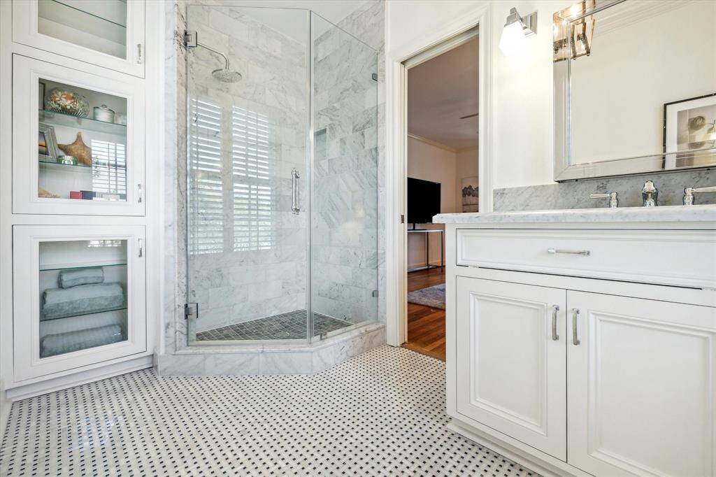 The master bath was renovated and has a marble, frameless glass shower enclosure, chrome plumbing fixtures, custom cabinetry and a mosaic marble floor.