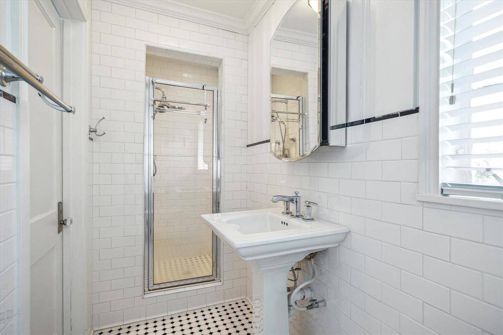 The bathroom in the guest suite has a shower enclosure, updated plumbing fixtures and mosaic, period-style tile floors.