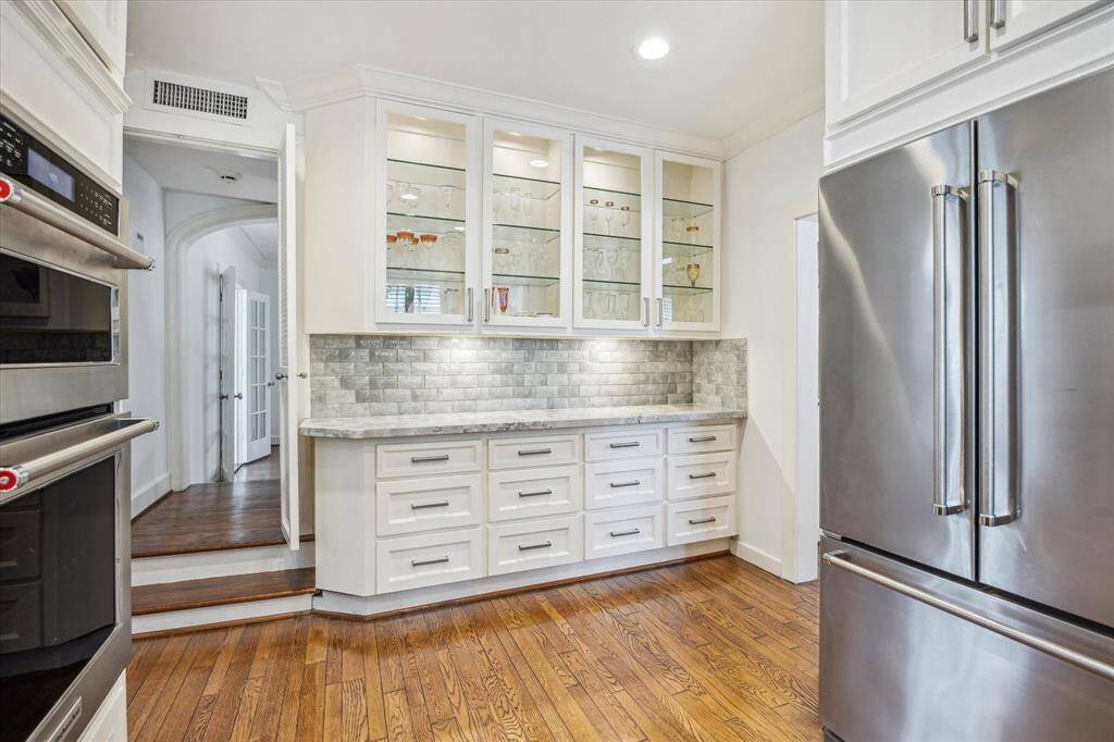 The kitchen was remodeled and features glass front cabinetry, marble counters, an updated glass tile backsplash with KitchenAid appliances.  The opening to the left leads to the family room or the stairs which deliver you to the second floor.