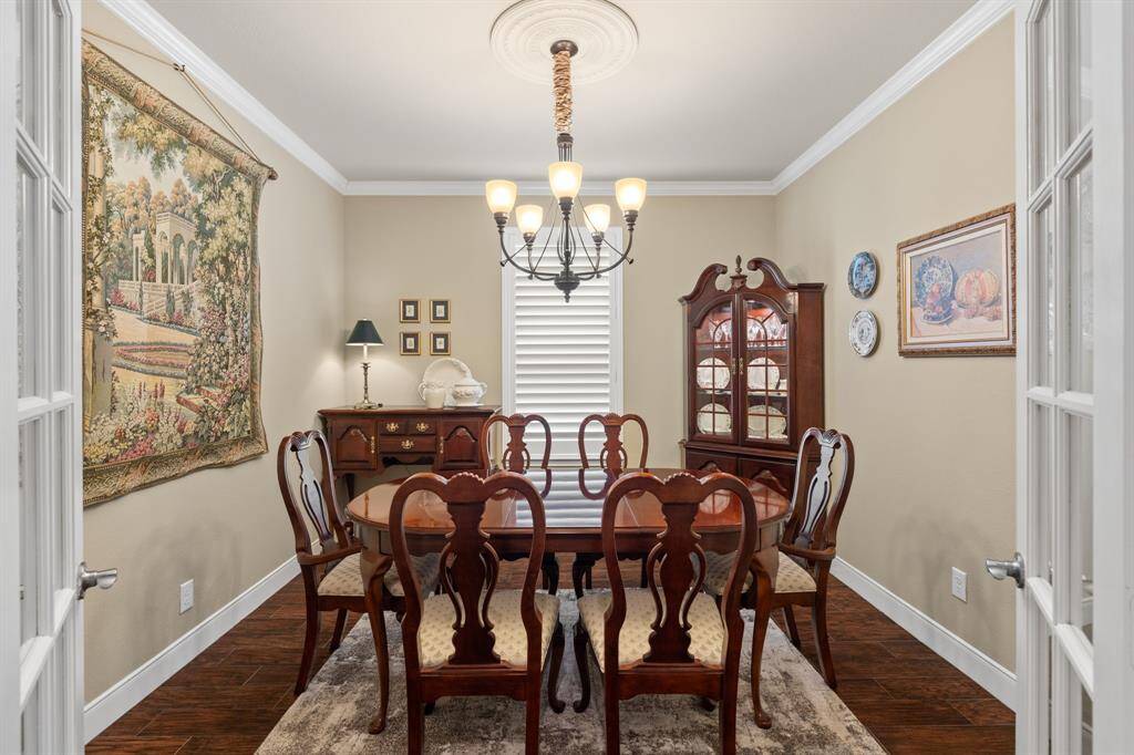 This versatile study/office easily transforms into a formal dining area. Notice the elegant ceiling medallion paired with a unique light fixture, charming shutters, wood-look tile flooring, and sparkling French doors that provide both style and privacy.