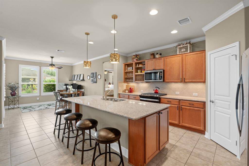 The large island offers plenty of space for bar stools, complemented by sleek pendant lighting and custom remodeled cabinets that blend modern and transitional styles.