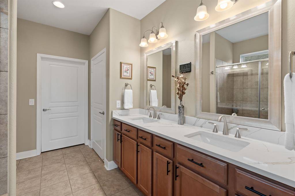 The owner’s bath features dual sinks, updated framed mirrors, sleek faucets and hardware, plus quartz countertops—offering a clean, modern, and refreshed feel.