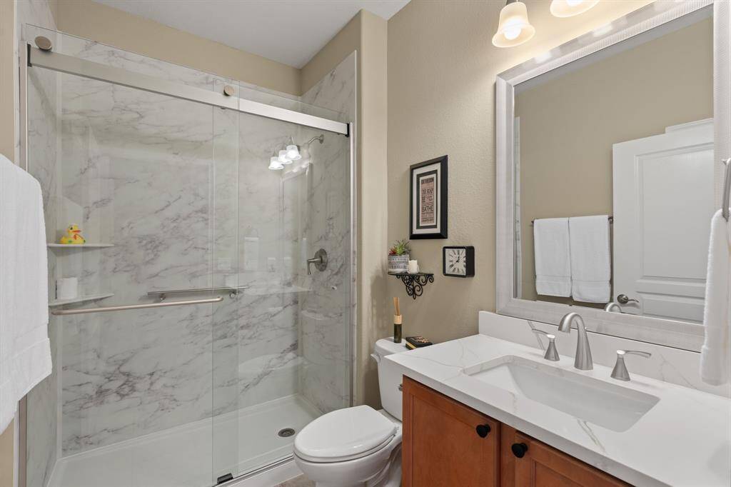 The updated guest bath features a sleek walk-in shower, stylish quartz countertops, framed mirrors, upgraded sink hardware, and modern rectangular sinks—delivering a fresh, clean look with contemporary flair.