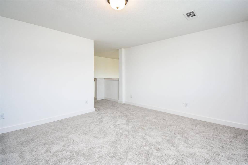 A spacious game room upstairs serves as a flexible retreat—ideal for recreation, media, or a quiet reading nook, illuminated by generous windows.