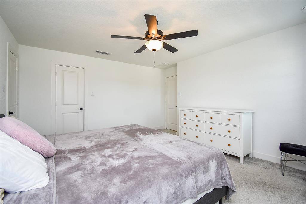 Spacious and calming, this additional bedroom features plush carpeting, a ceiling fan, and enough room for personalization without compromise.