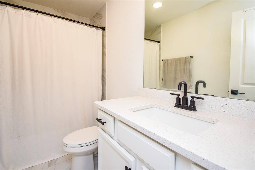 Fresh and polished, this full bath includes a pristine white vanity and black accents.