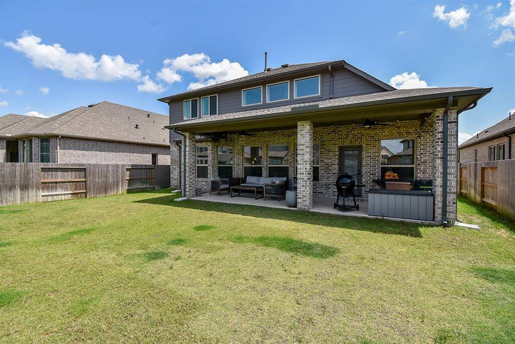 From the yard, the back of the home reveals its full potential—an inviting patio nestled beneath a broad overhang, perfectly connected to the lush lawn.