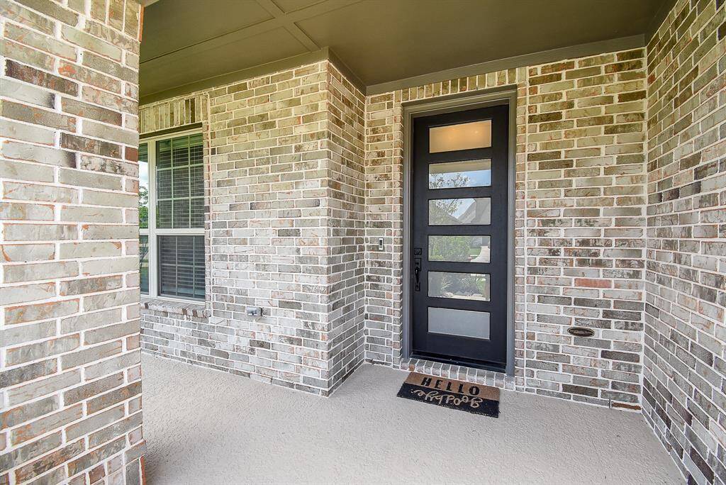 Sheltered by an extended porch, the front entry offers a welcoming pause before stepping inside—complete with a stylish door that hints at the thoughtful interiors beyond.