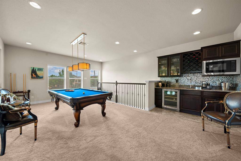 With a built in mini kitchen this gameroom has a beverage fridge, microwave, wine storage and a sink