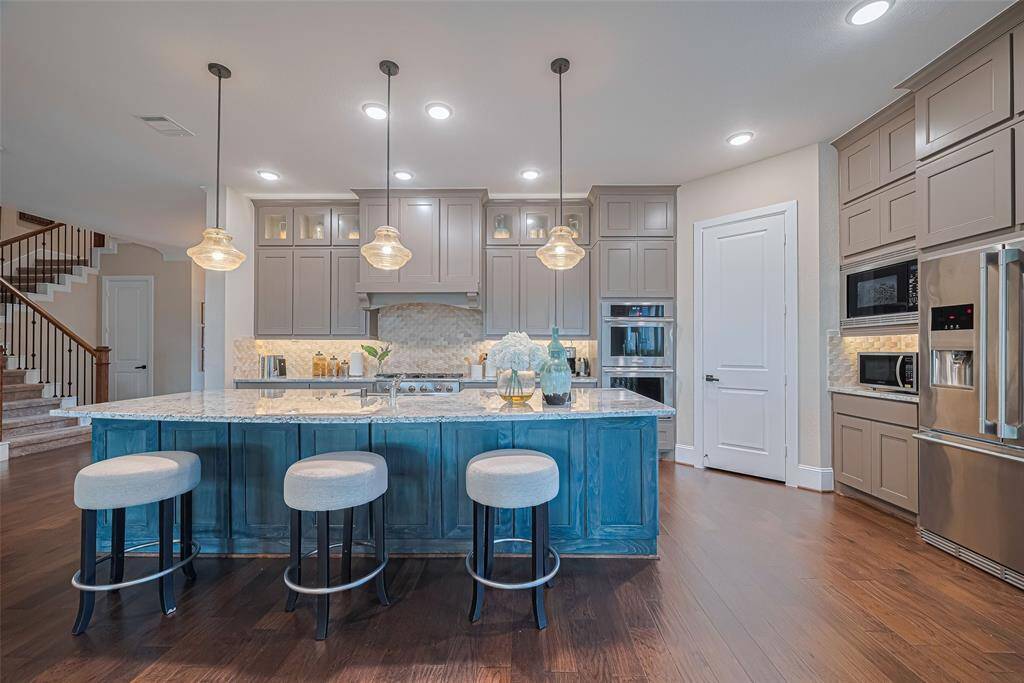 What a dream kitchen with floor to ceiling cabinets, huge central island, beautiful designer pendant lighting, and breakfast seating.