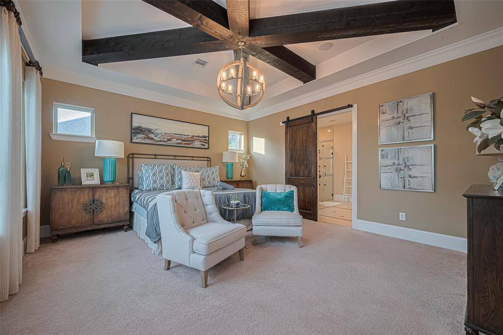 Outstanding primary bedroom space with Tray ceilings filled with architecturalbeams and enough room for seating as well as a fantastic barn style door to the en suite