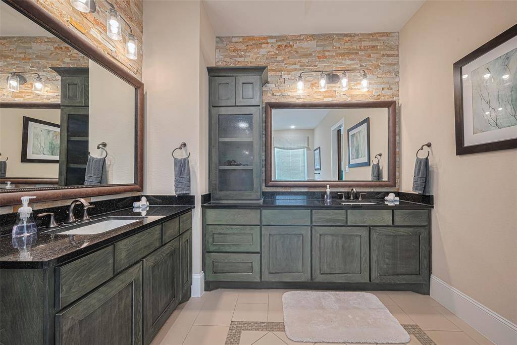 Double vanity and oversize mirror with stone feature wall and custom stained cabinet cabinets