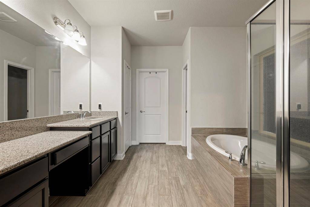 Retreat to the luxurious primary suite, conveniently located on the main level for ultimate privacy and ease. The spa-like en-suite bathroom is a true oasis, complete with a relaxing garden tub, a separate walk-in shower, and a vanity, offering a serene escape at the end of the day.