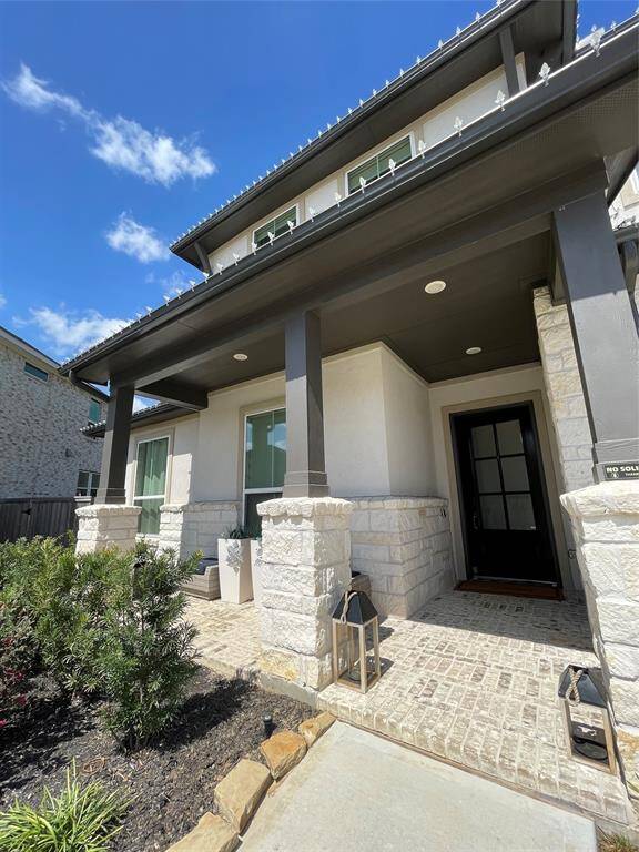 Covered front porch, creating a welcoming transition between the outdoors and the home. Brick flooring complementing the home's architectural style.