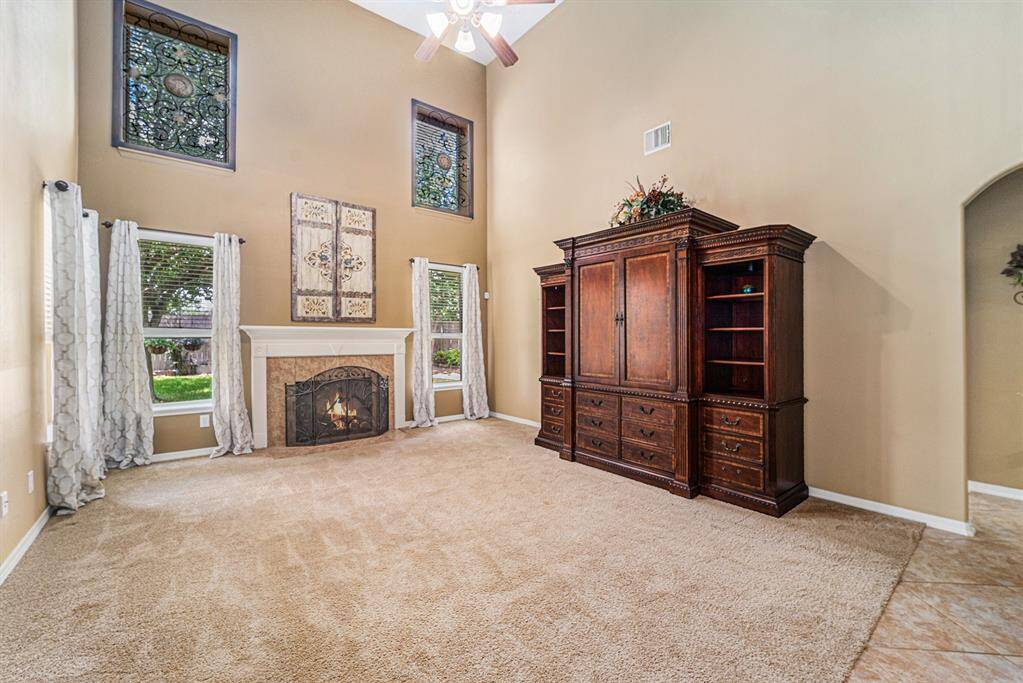A grand 2-story family room offers plenty of light as windows flank the fireplace with wooden mantel!