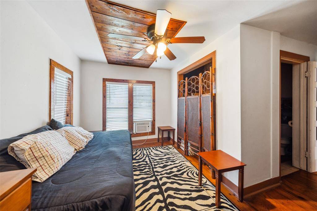 Guest house bedroom #2/office with ceiling fan, window ac, and window blinds.