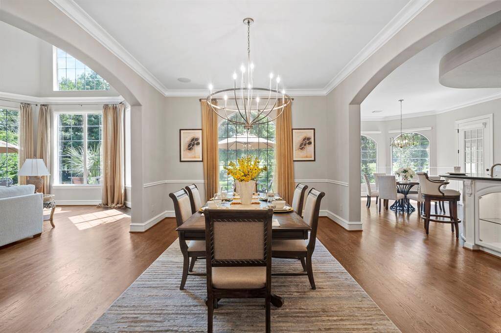This dining room is bathed in naturallight streaming through expansivewindows and has a beautiful chandelier.