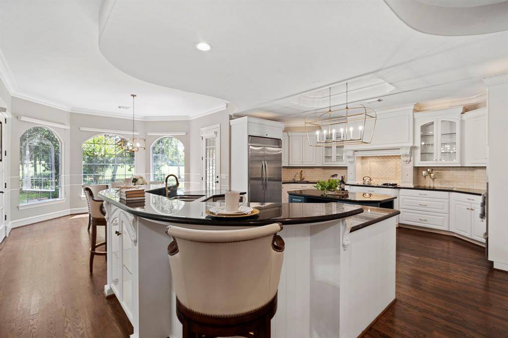 The kitchen features new light fixtures and hardware, oversized walk-in pantry, Miele cooktop, built-in refrigerator, dual sinks and islands, and under cabinet lighting.