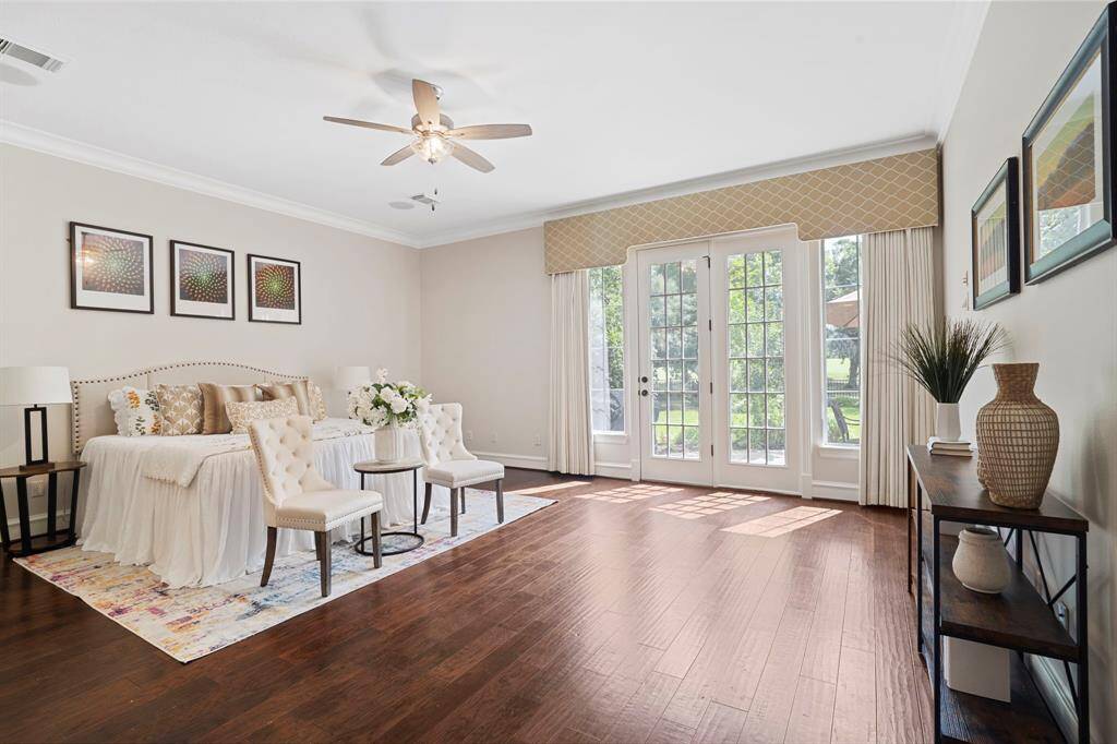Step into the sanctuary of theprimary bedroom featuring beautiful floors, crown molding, and access to the back patio.
