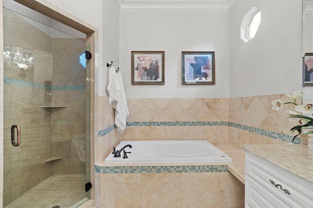 The primary walk-in shower features tile surround and glass door.
