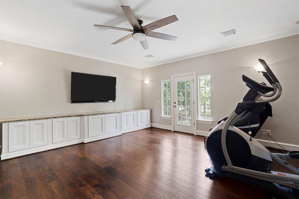 The upstairs game room features beautiful floors, crown molding, ceiling fan, and access to the outdoor balcony.